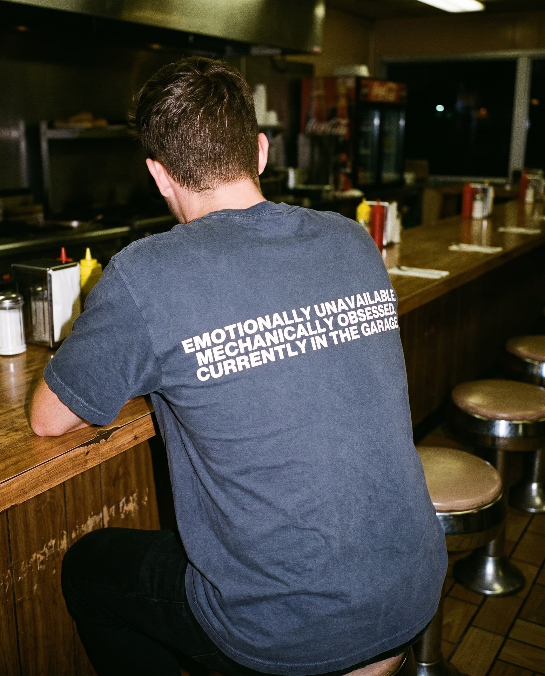 Back view of the "EMOTIONALLY UNAVAILABLE. MECHANICALLY OBSESSED. CURRENTLY IN THE GARAGE." tee